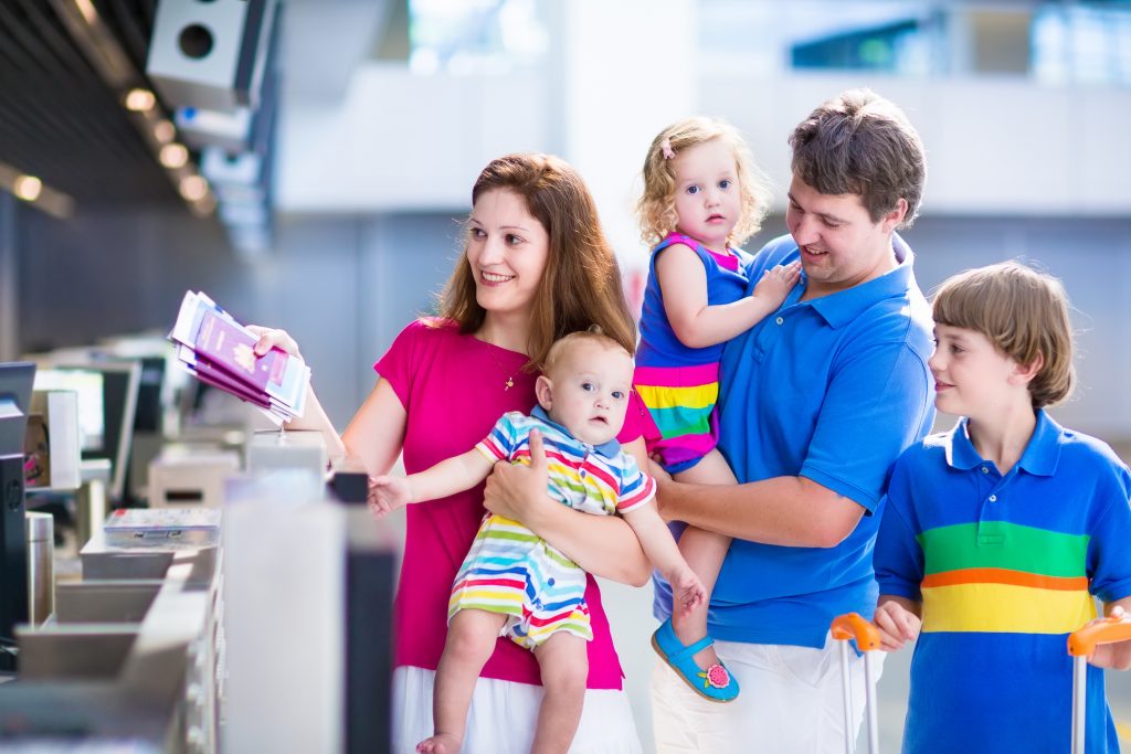 Big happy family with three kids traveling by airplane at Dusseldorf International airport, parents with teenager boy, toddler girl and little baby holding colorful luggage for summer beach vacation